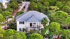 A coastal house with a grey roof, surrounded by dense green pine trees. - Prince of Tides - 6 BEDROOM with POOL+ELEVATOR - SHORT WALK TO BEACH (Eastpoint)