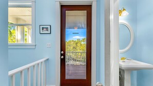 A door with a view of a balcony and trees, a white railing, and a white sink with a gold faucet. - Prince of Tides - 6 BEDROOM with POOL+ELEVATOR - SHORT WALK TO BEACH (Eastpoint)