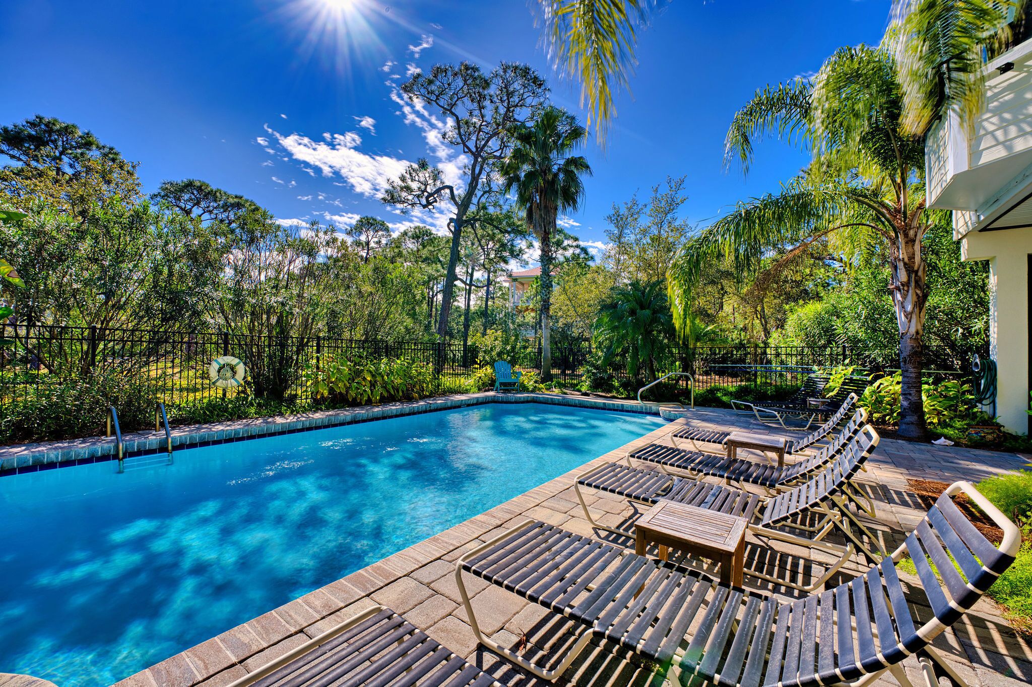 A swimming pool with lounge chairs and a fence.