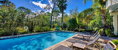 A swimming pool with lounge chairs and a fence.