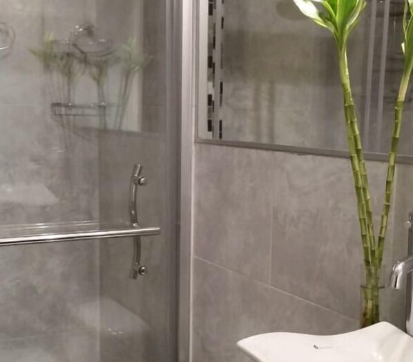 A bathroom with a glass-enclosed shower, a white sink, and a bamboo plant. - Condo 3BR-2BH La Mariscal, free WiFi (Quito)