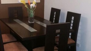 Ein Esstisch mit vier Stühlen, einer Vase mit Blumen und einem Wanddekor.