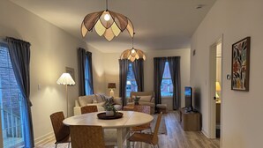 Ein modernes Wohnzimmer mit Essbereich, ausgestattet mit einem runden Tisch, Holzstühlen, einer Couch und einer Zierpflanze.