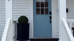Eine Fassadenansicht eines Hauses mit blauer Tür, weißer Fassade und schwarzem Briefkasten.
