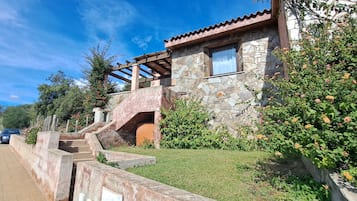 Un edificio in pietra con una pergola in legno e una scalinata che conduce all'ingresso.