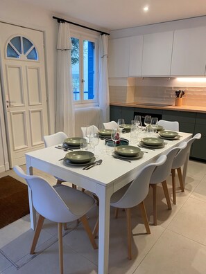 A dining area with a white table set for six, surrounded by white chairs.