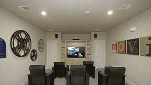 Una sala de conferencias con una televisión, varias sillas y una pared con obras de arte enmarcadas.