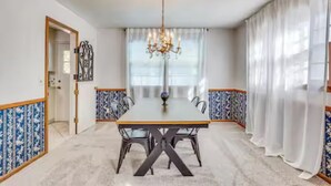 Comedor con una larga mesa, sillas, un candelabro y papel tapiz estampado.