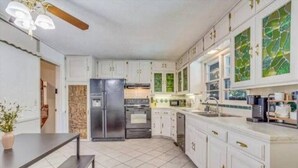 Una cocina moderna con armarios blancos, un refrigerador de acero inoxidable y una mesa de comedor de madera.