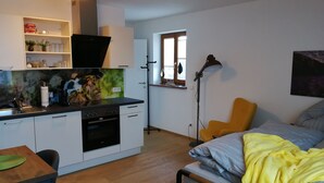 A compact living space with a kitchenette, a dining area, and a bed. - Quartier No.7 - Serviced living at the gates of Salzburg (Grödig)