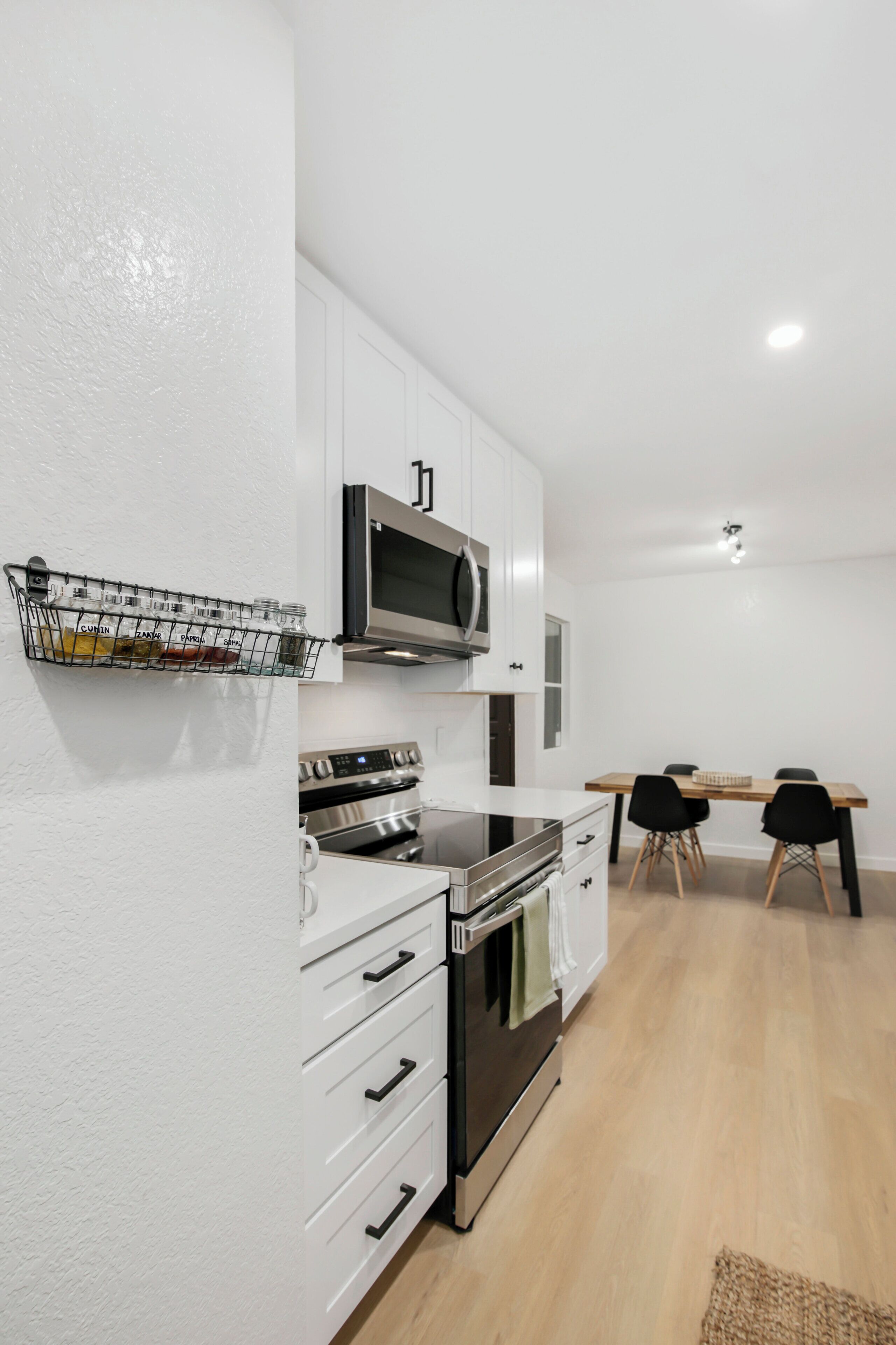 A modern kitchen with white cabinets, stainless steel appliances, and a black countertop.