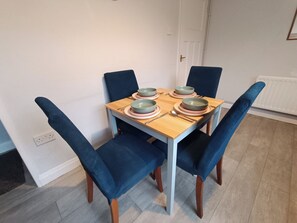 Une table à manger avec quatre chaises, un ensemble de bols et des couverts.