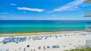 Une plage bordée de rangées de chaises longues et de parasols, un ciel bleu azur et l’océan en toile de fond.