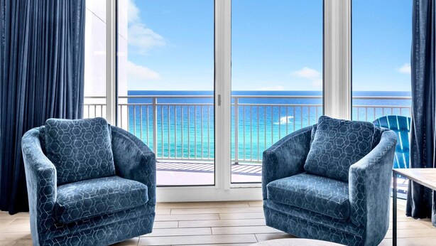 Un balcon avec vue sur l’océan, deux fauteuils et une table.