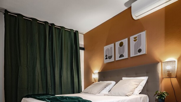 Een moderne slaapkamer met een bed, een bedlampje en een klein tafeltje met een plant.