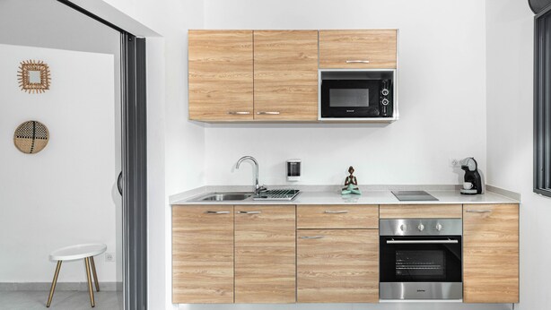 Una cuina moderna amb armaris de fusta, un forn d'acer inoxidable i un microones.