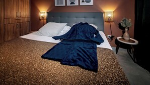 Un dormitori amb llit, armari, taula de nit amb làmpada i obra d'art a la paret.