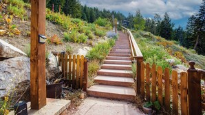 A wooden staircase leading uphill with a metal railing on one side and a wooden fence on the other.