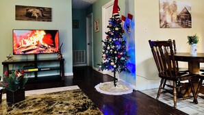 A living room with a fireplace, a Christmas tree, and a dining area with a table and chairs. - Charming Cozy Cabin in a PEACFUL MOUNTAIN setting w HOTTUB! Close to PigeonForge (Seymour)