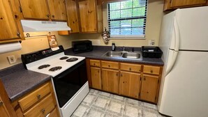 A kitchen with wooden cabinets, a white stove, a sink, and a refrigerator. - Charming Cozy Cabin in a PEACFUL MOUNTAIN setting w HOTTUB! Close to PigeonForge (Seymour)