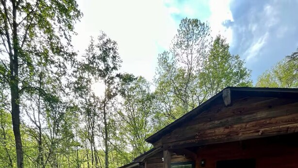 A wooden cabin with a porch, a circular window, and a stone fire pit. - Charming Cozy Cabin in a PEACFUL MOUNTAIN setting w HOTTUB! Close to PigeonForge (Seymour)