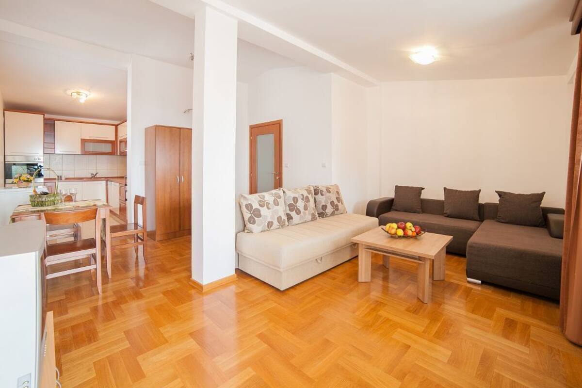 A modern living room with a sofa, a coffee table with fruit, and a dining area with a table and chairs.