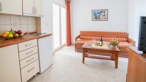 A compact living space with a kitchenette, a sofa, a coffee table, and a television. - Ivan Apartmani (Petrovac)