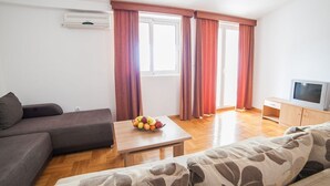 A living room with a sofa, a coffee table with fruit, a TV, and a cabinet. - Ivan Apartmani (Petrovac)