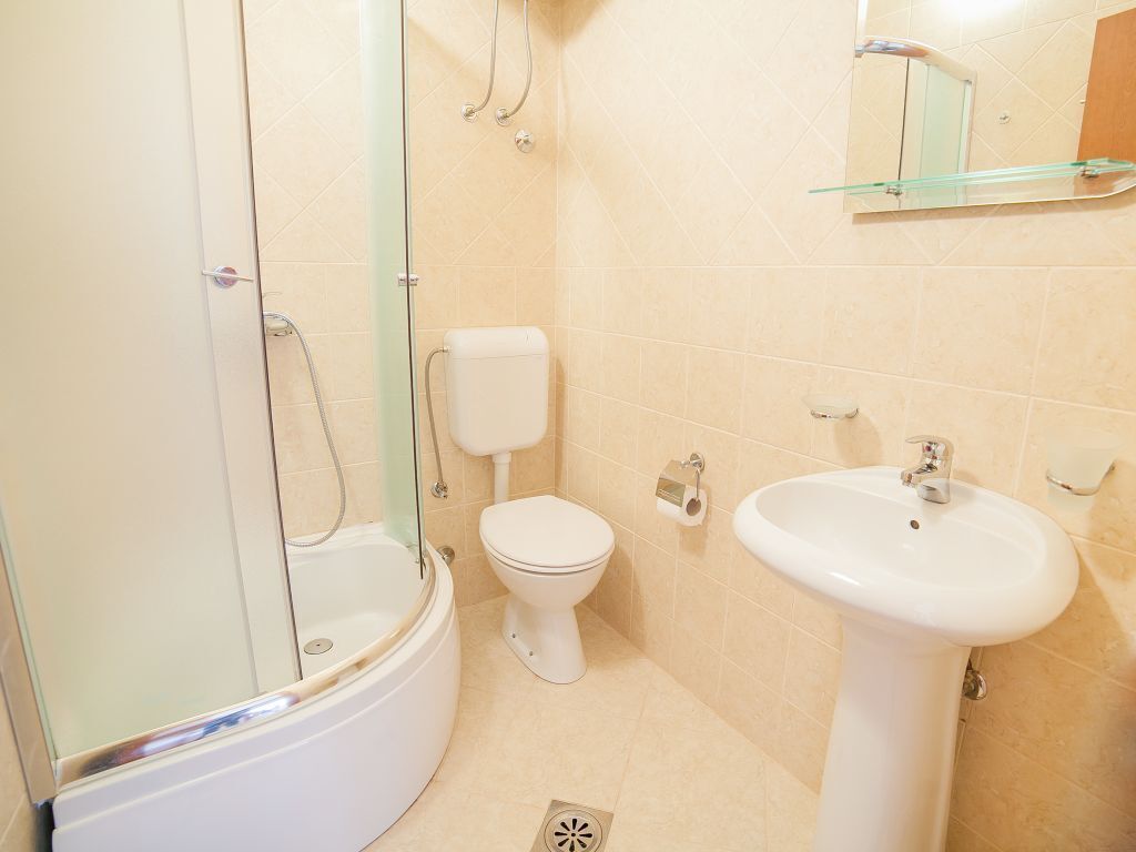 Une salle de bain avec une douche à parois de verre, des toilettes et un lavabo sur colonne.