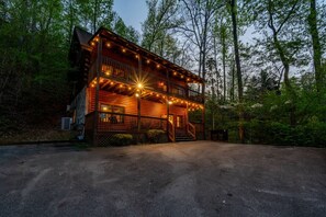 A two-story log cabin with a porch, surrounded by trees. - Prime Location! 1mi to Parkway, Sauna, Game Room! (Pigeon Forge)
