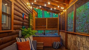Un chalet confortable avec un intérieur en bois, un mur en pierre, un jacuzzi et une vue sur la forêt.