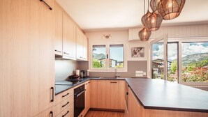 Eine moderne Küche mit Holzausstattung, einer schwarzen Arbeitsplatte und einem großen Fenster mit Blick auf eine Berglandschaft.