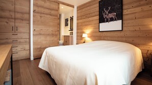 Ein Schlafzimmer mit einem großen Bett, Holzwänden, einem Holzschrank und einem gerahmten Bild von Hirschen.