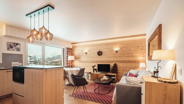 Eine moderne Küche mit Kochinsel, Essbereich mit Stühlen, einer Couch und einem Fernseher.