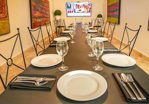 A long dining table with chairs, set with plates, glasses, and cutlery, in a room with artwork on the walls. - Casa Condado Hotel & Residences: Superior room (San Juan)