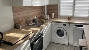 Une cuisine moderne dotée d’un plan de travail en bois, d’un évier en acier inoxydable et d’un lave-linge encastré.