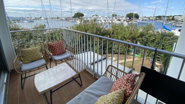 A balcony with wicker furniture, a glass table, and a view of a marina with boats. - Sol-y-Days la Santa Maria marinas view (Le Grau-du-Roi)