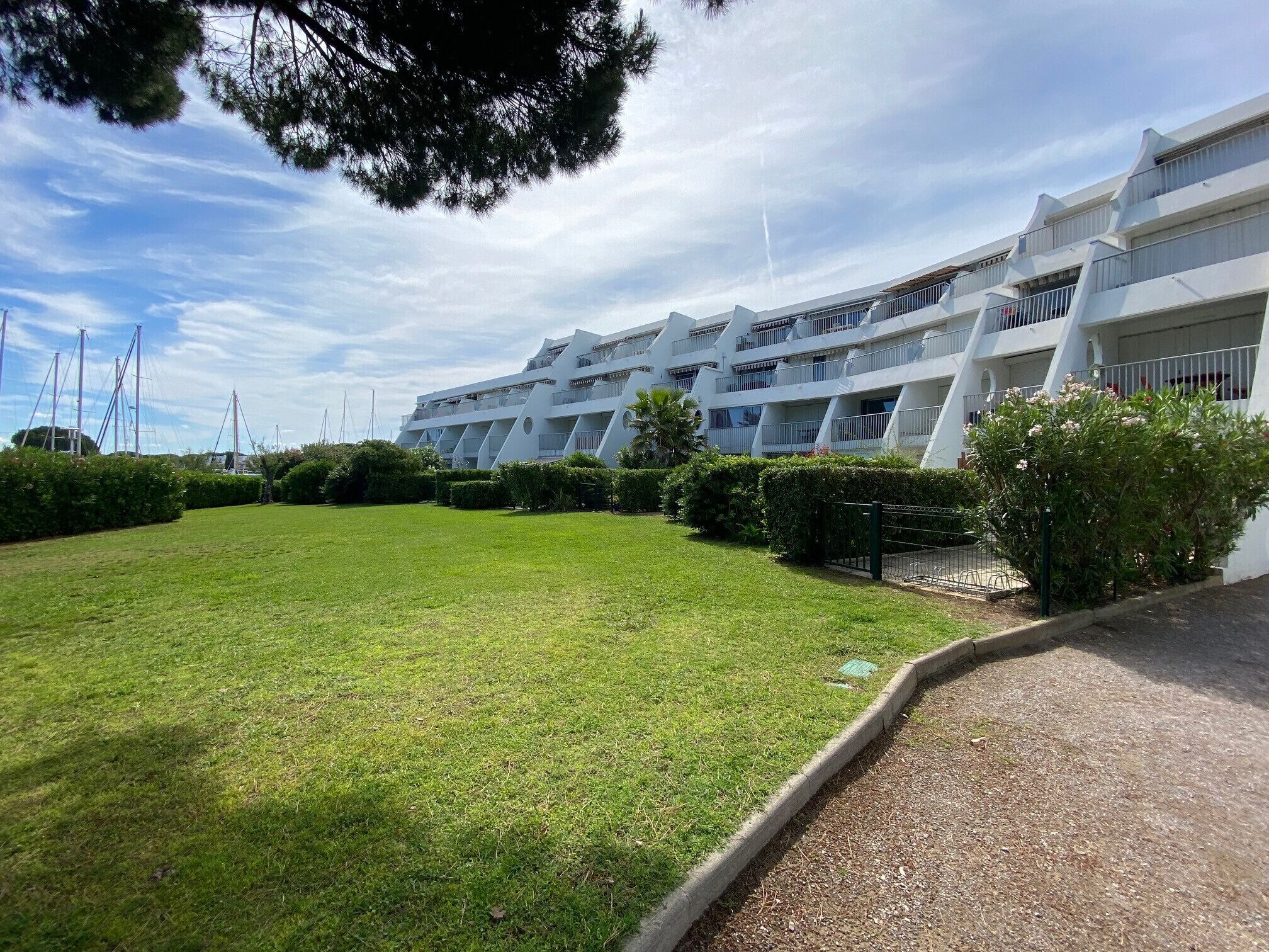 A modern multi-story hotel with a well-maintained lawn and a clear sky.