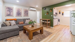 A living room with a grey sofa, a wooden coffee table, and a patterned rug. - Emerald Escape - UNR & Pet Friendly - Fenced Yard (Reno)