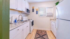 A compact kitchen with white cabinets, a microwave, a stove, and a refrigerator. - Emerald Escape - UNR & Pet Friendly - Fenced Yard (Reno)