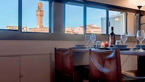 A dining area with a table set for two, a candle, and a bottle of wine. - SKYLINE FLORENCE APARTMENT (Firenze)