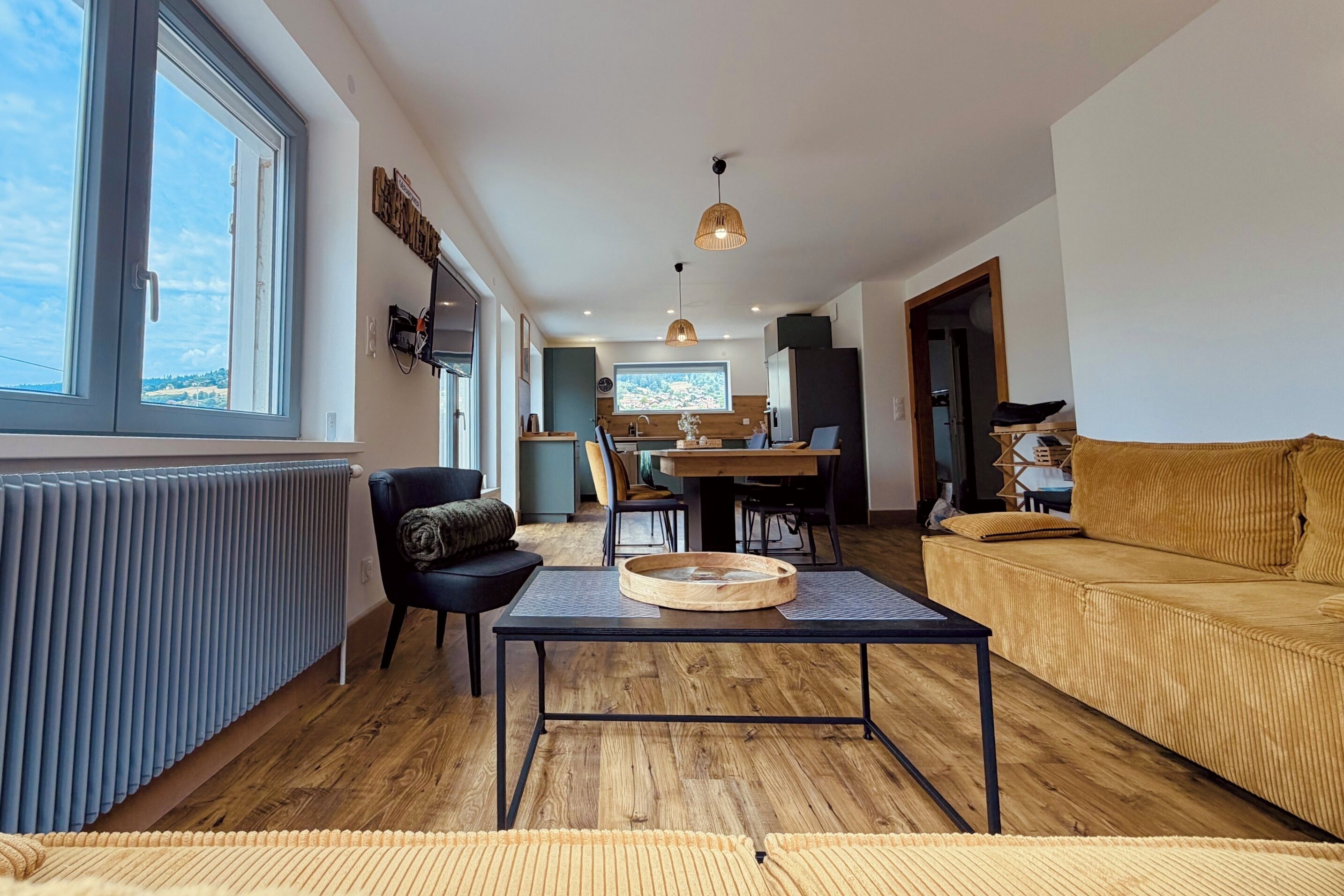A modern living room with a sofa, a dining table, and a kitchen in the background.