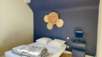 Een slaapkamer met een bed, nachtkastjes, een lamp en een wanddecoratie.
