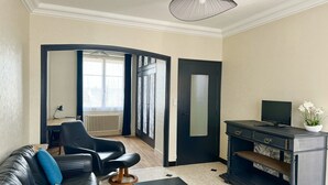 A living room with a black leather sofa, a black coffee table, a black TV stand, and a black pendant light.