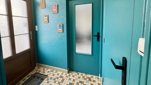 A teal-walled hallway with a door, a window with blinds, and three cork bulletin boards.