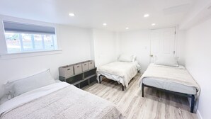 A bedroom with two beds, a window, and storage boxes. - Cozy and bright 6-bedroom house in Renton (Kent)