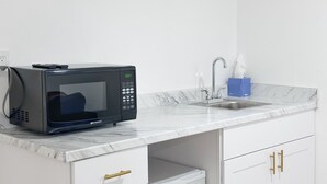 A compact kitchenette with a black microwave, a sink, and a marble countertop. - Cozy and bright 6-bedroom house in Renton (Kent)
