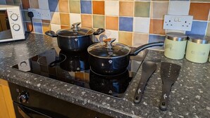 Eine Küche mit einem Gaskochfeld, zwei Töpfen, einem Wasserkocher und einer Kaffeemaschine.