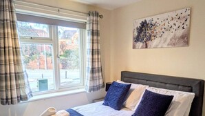 A hotel room with a bed, pillows, a window with curtains, and a painting on the wall. - Theatre Severn Town House, Parking & Quarry Views (Shropshire)