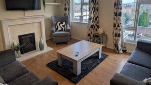 Ein Wohnzimmer mit Kamin, Fernseher, Sofa und Couchtisch.